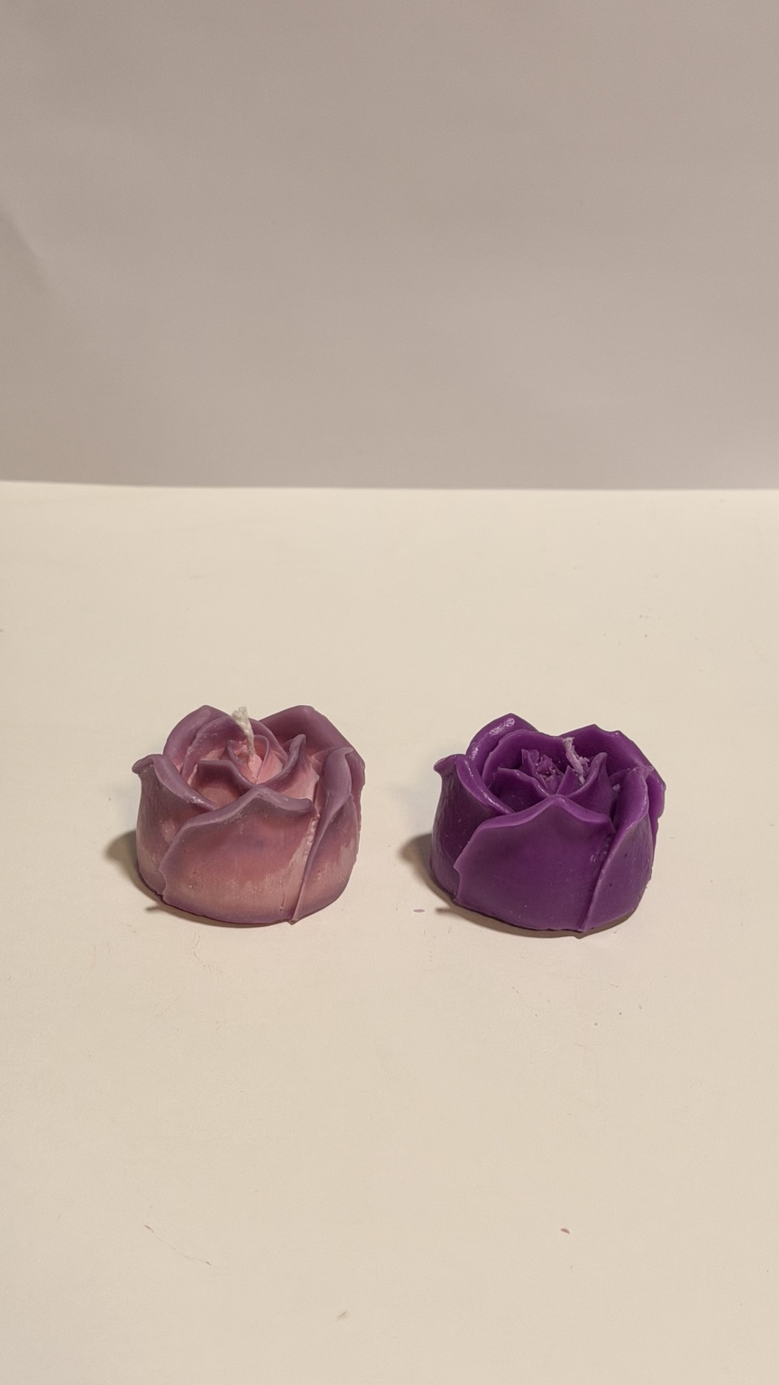 Two handmade House of Dee rose candles in soft pink and deep purple